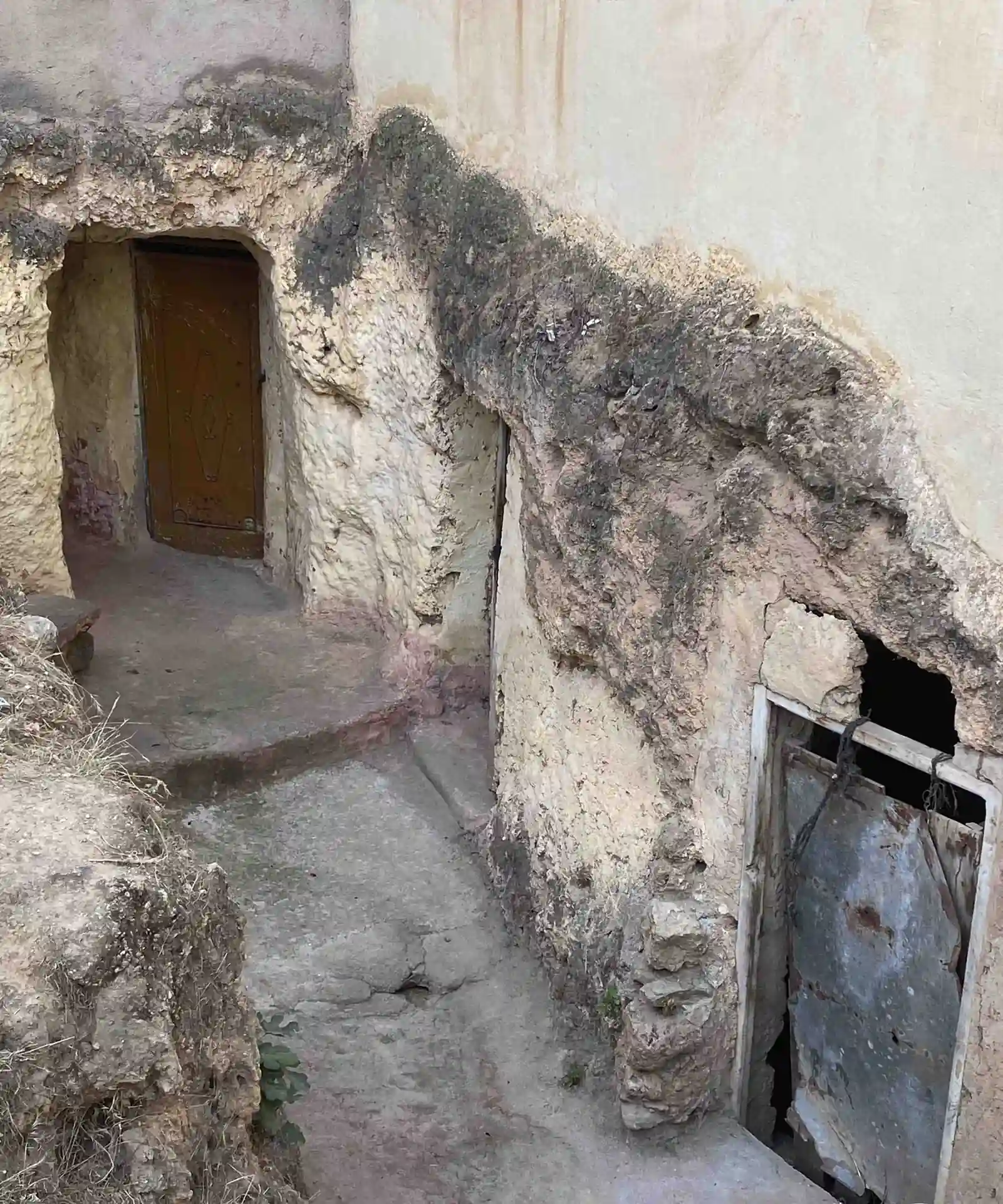 Due ingressi di grotta scavati nel calcare eroso accanto a un sentiero stretto