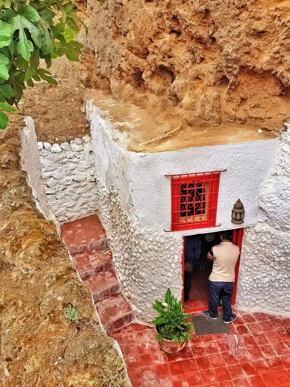 Ingresso con cornice rossa a uno spazio-grotta ricavato nella roccia