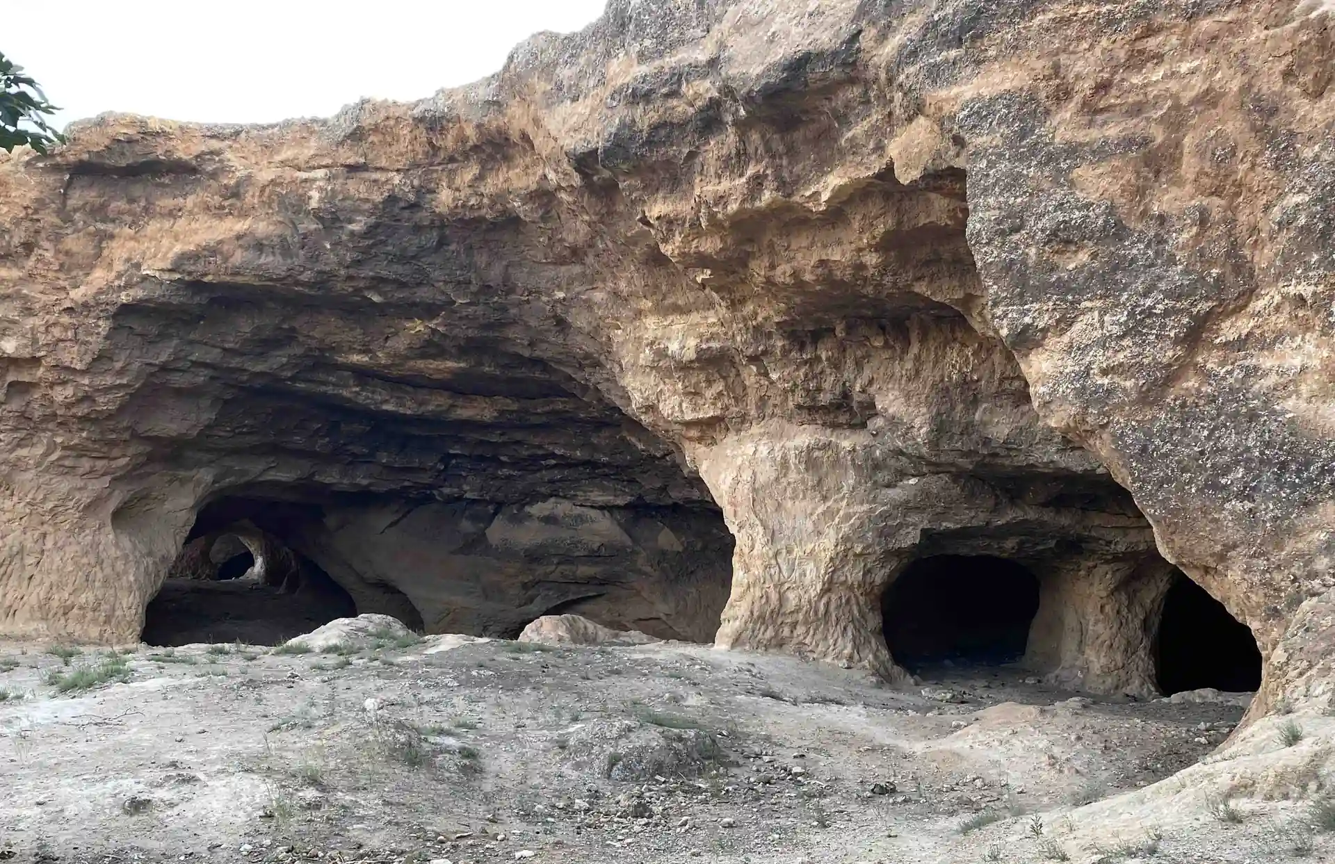 Ampio gruppo di aperture scure di grotte nel calcare stratificato vicino a Bhalil