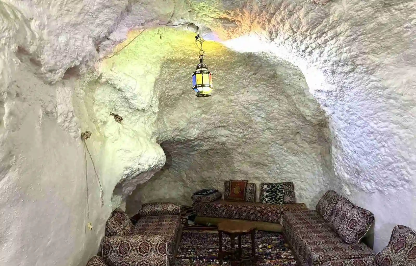 Salone in grotta ristrutturato, bianco, con sedute tradizionali e una lanterna sospesa