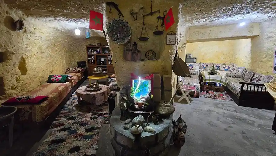 Ampio interno in grotta ristrutturato a più ambienti, con sedute e oggetti domestici