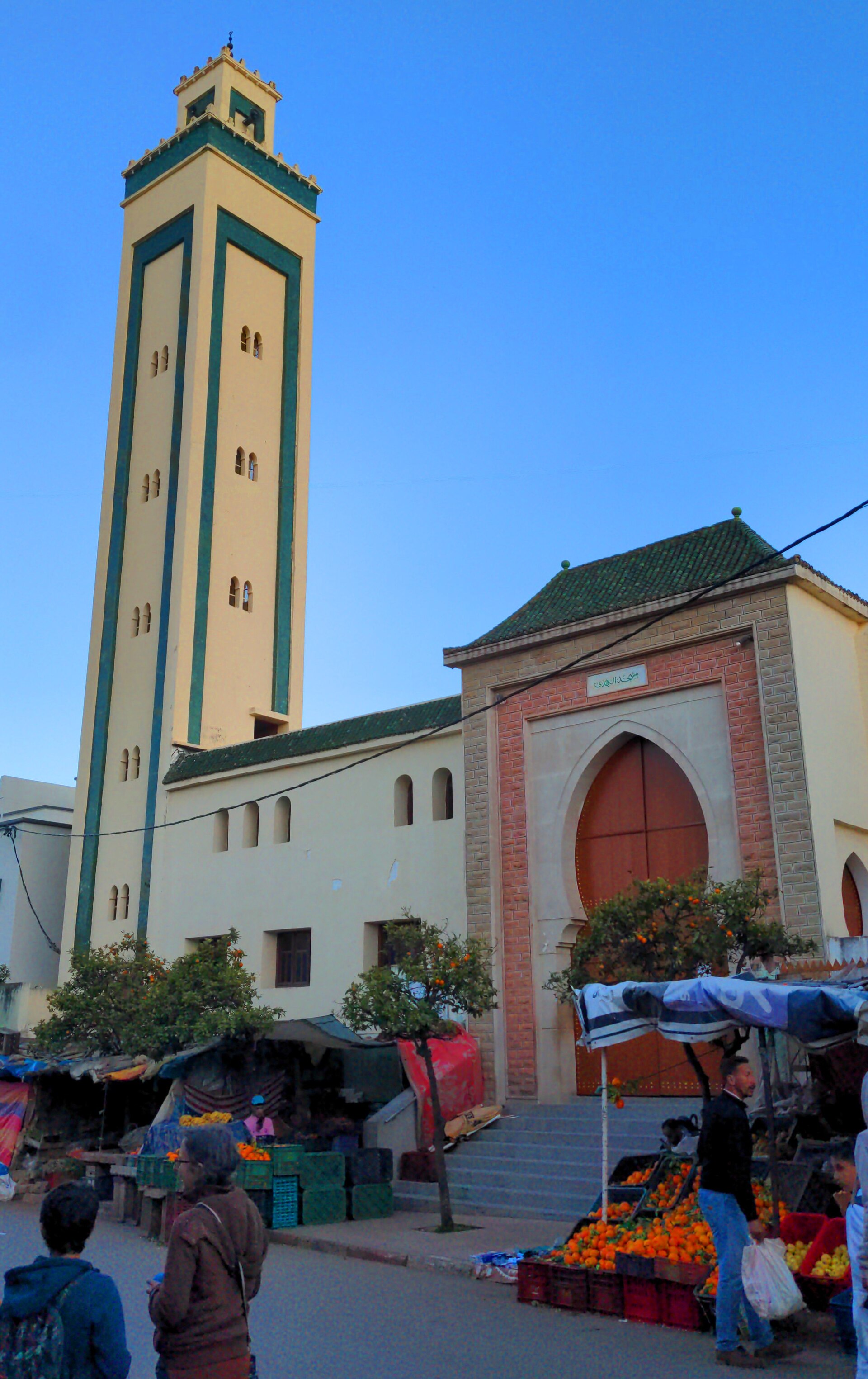 La moschea di Bhalil sopra le bancarelle di frutta in una via di mercato affollata