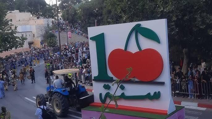 A large cherry-themed float moving through crowds during the Sefrou Cherry Festival carnival