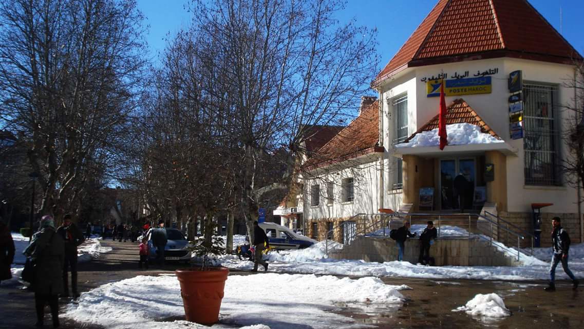 Snow-covered street and red-roofed post office in central Ifrane