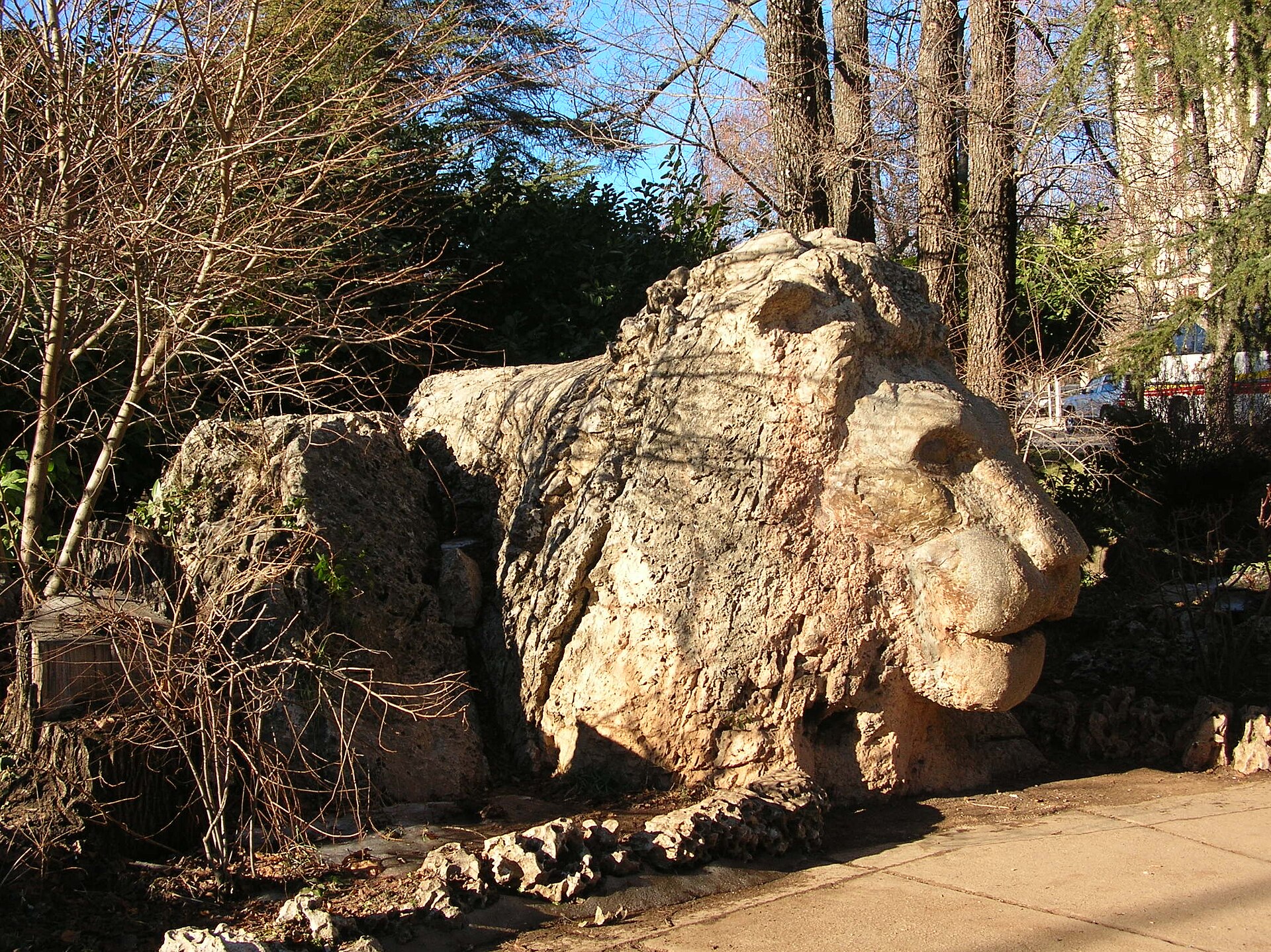 Large carved stone lion beneath trees in Ifrane