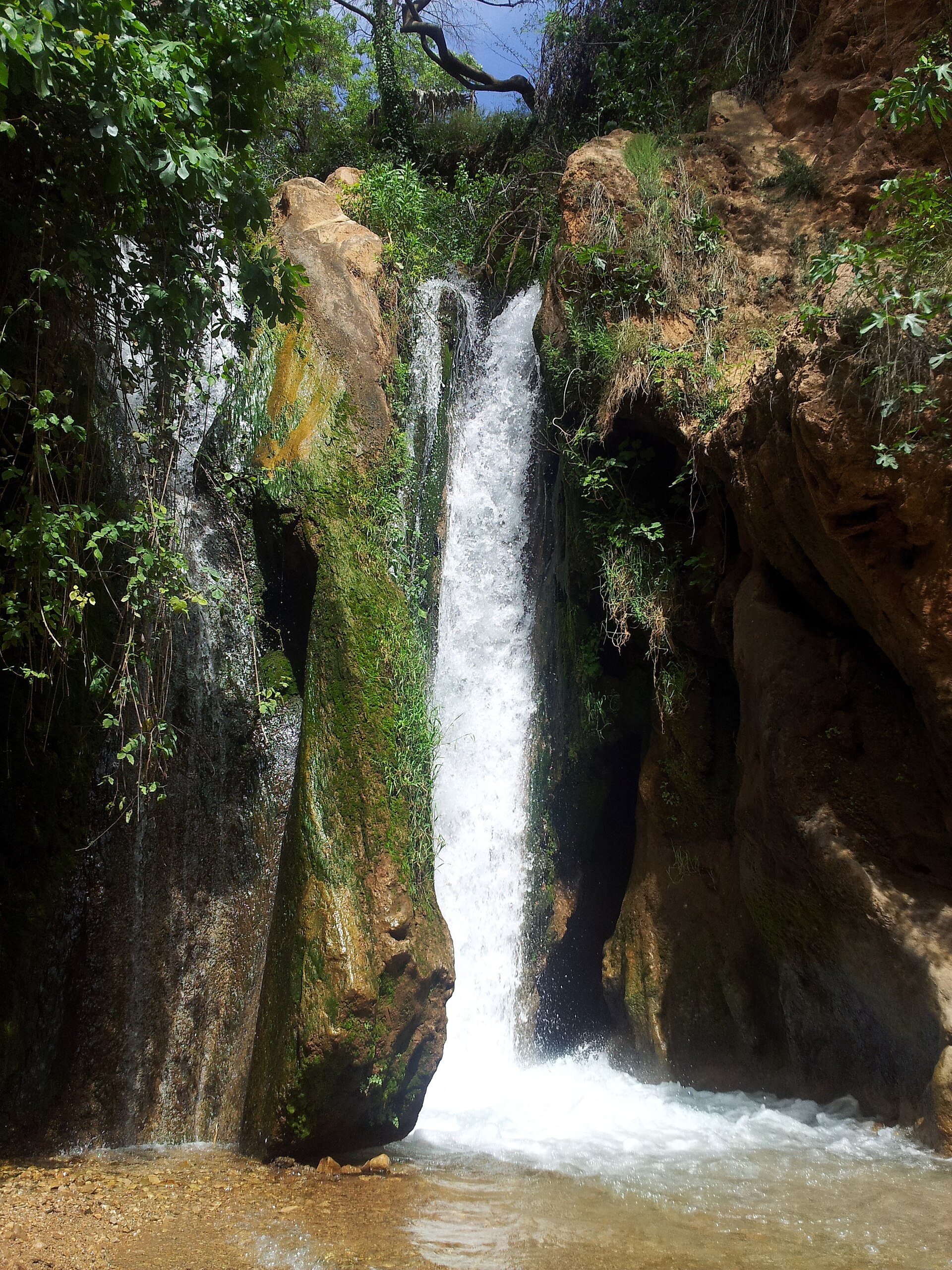 Close vertical view of Sefrou waterfall flowing between mossy rocks