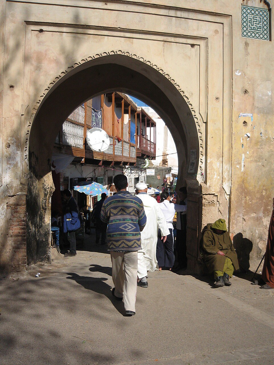 Residents passing through a decorated arched gate in Sefrou medina